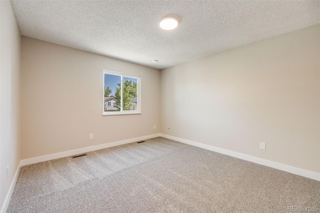 spare room featuring carpet, a textured ceiling, visible vents, and baseboards