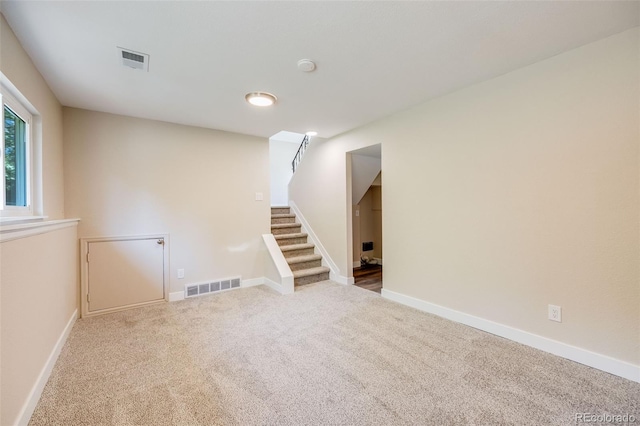 spare room with baseboards, visible vents, carpet flooring, and stairs