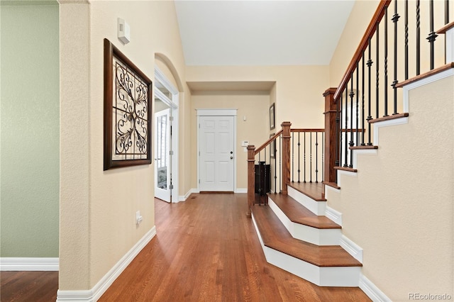 foyer entrance with stairway, wood finished floors, and baseboards