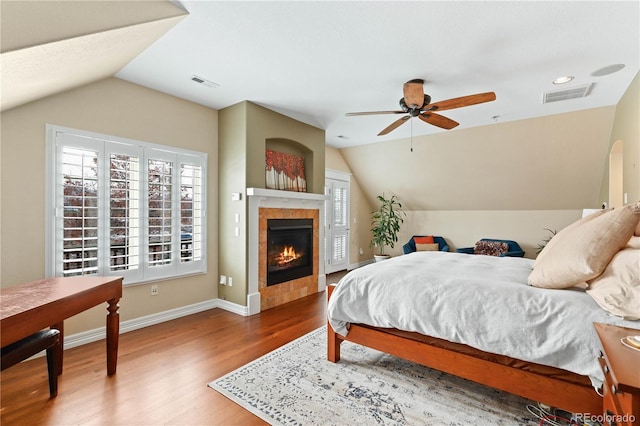 bedroom featuring lofted ceiling, visible vents, multiple windows, and wood finished floors