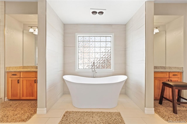 bathroom featuring a freestanding tub, tile patterned floors, tile walls, and vanity