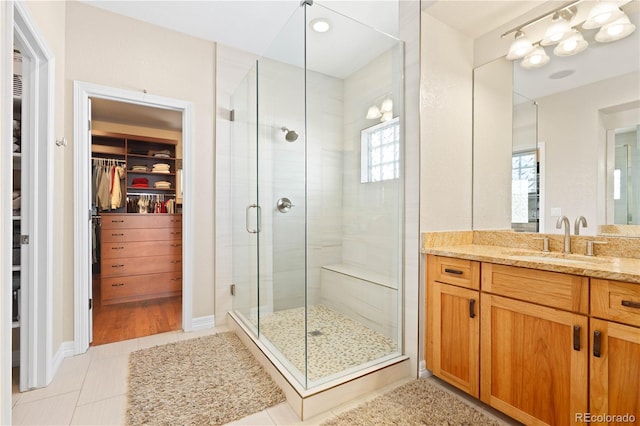 bathroom featuring plenty of natural light, a shower stall, vanity, and a spacious closet