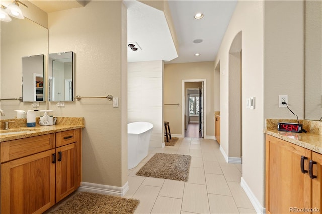 full bath featuring a freestanding tub, recessed lighting, vanity, baseboards, and tile patterned floors