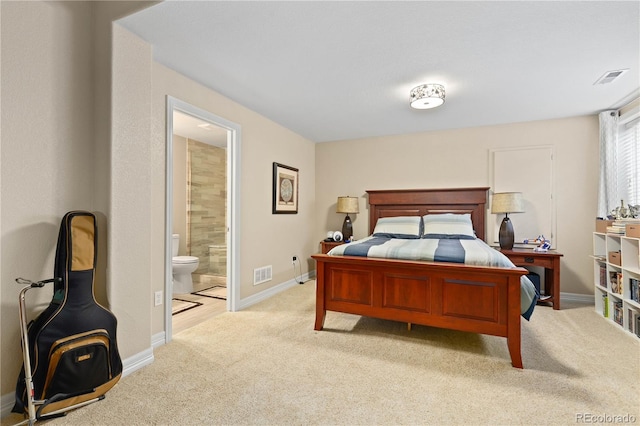 bedroom with ensuite bath, baseboards, visible vents, and light colored carpet