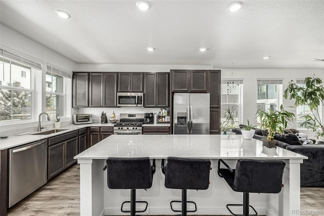 1500 Sun Way, Lafayette, CO 80026 - kitchen with stainless steel appliances, a sink, light wood-type flooring, light stone counters, and a kitchen island