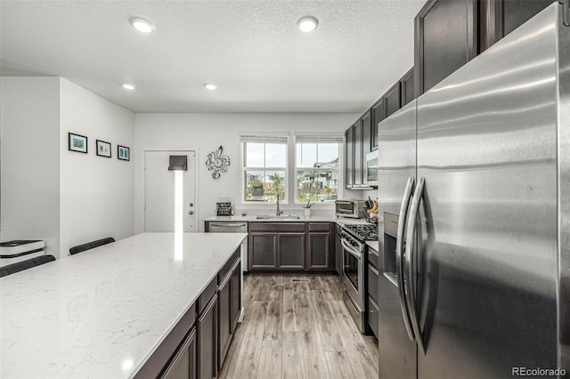 1500 Sun Way, Lafayette, CO 80026 - kitchen featuring appliances with stainless steel finishes, a sink, light wood-style flooring, light stone counters, and dark brown cabinetry