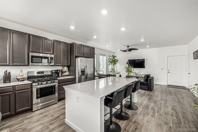 1500 Sun Way, Lafayette, CO 80026 - kitchen featuring appliances with stainless steel finishes, dark brown cabinetry, a breakfast bar, light wood-type flooring, and recessed lighting