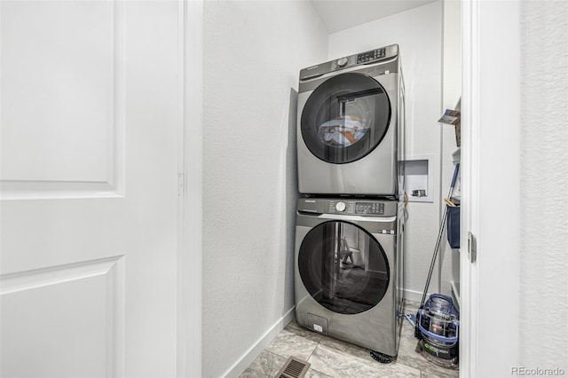 1500 Sun Way, Lafayette, CO 80026 - laundry room featuring estacked washer and dryer, baseboards, marble look tiles, and a textured wall