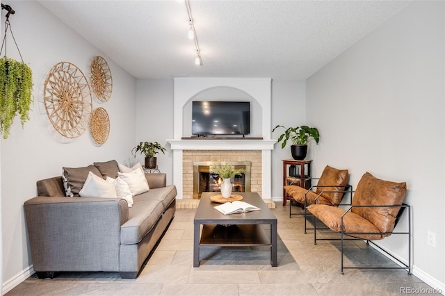 3889 S Fraser St, Aurora, CO 80014 - living area featuring a fireplace, track lighting, a textured ceiling, and baseboards