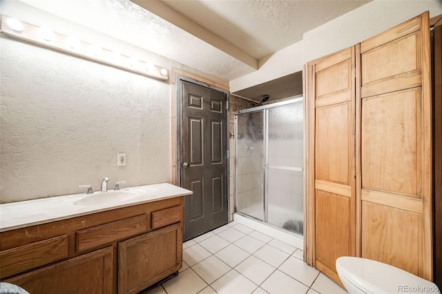 46 Apache Rd, Evergreen, CO 80439 - bathroom featuring vanity, a stall shower, a textured wall, tile patterned flooring, and toilet