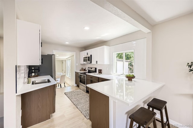 1750 S Zuni St, Denver, CO 80223 - kitchen with stainless steel appliances, a breakfast bar, light countertops, white cabinets, and recessed lighting