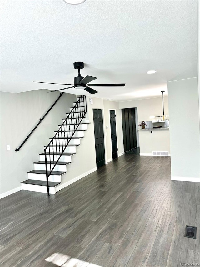 unfurnished living room with ceiling fan, dark hardwood / wood-style flooring, and a textured ceiling