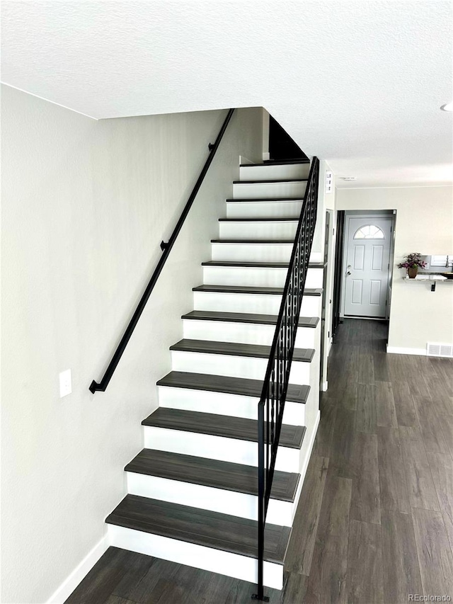 stairs featuring hardwood / wood-style floors and a textured ceiling