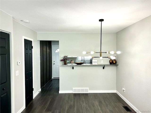 kitchen with decorative light fixtures, dark hardwood / wood-style floors, kitchen peninsula, and a chandelier