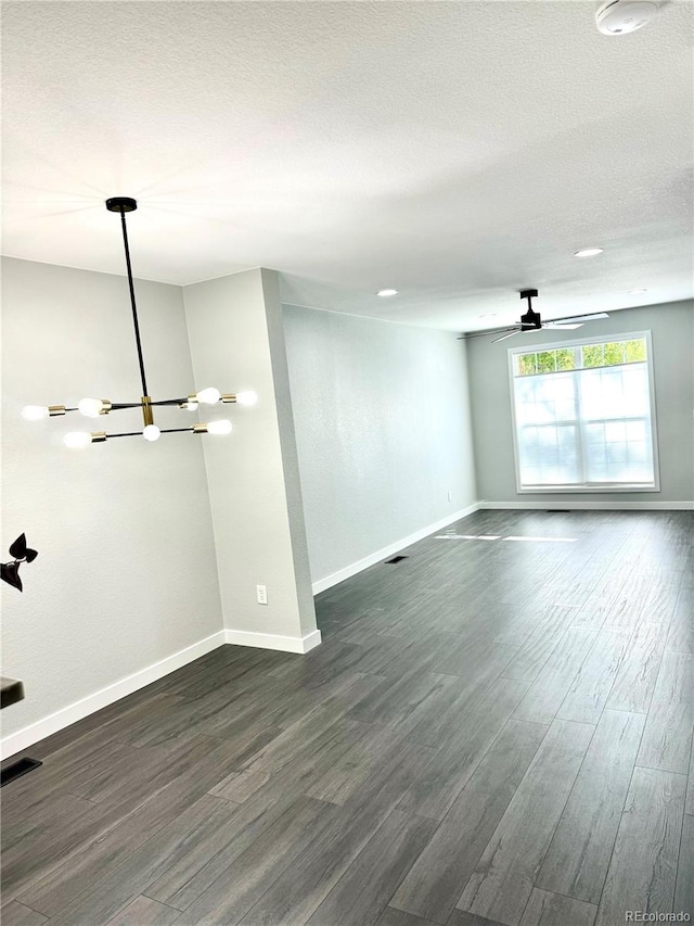 unfurnished room with a textured ceiling, dark hardwood / wood-style floors, and ceiling fan with notable chandelier