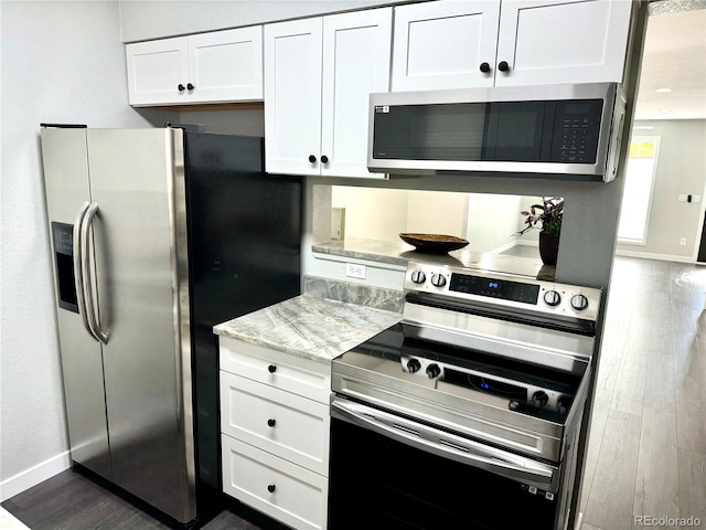 kitchen with light stone counters, white cabinetry, and stainless steel appliances