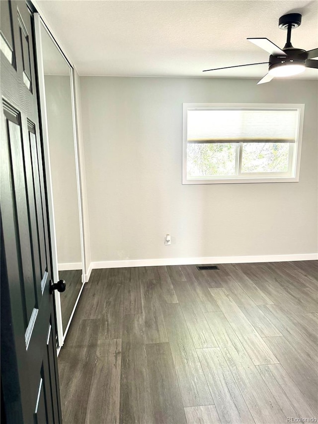 unfurnished bedroom featuring multiple windows, ceiling fan, and dark hardwood / wood-style floors