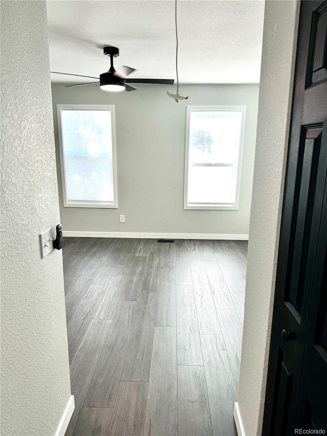 empty room featuring hardwood / wood-style floors, ceiling fan, and a textured ceiling