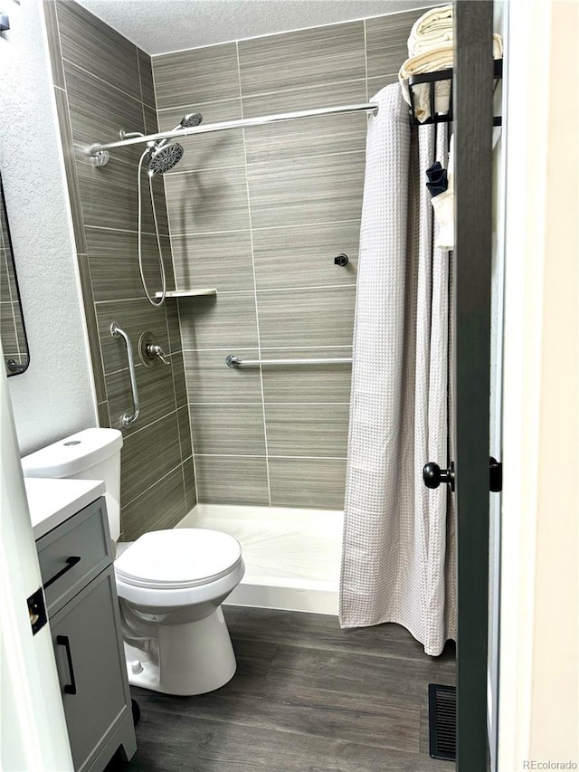 bathroom featuring vanity, toilet, a textured ceiling, curtained shower, and wood-type flooring