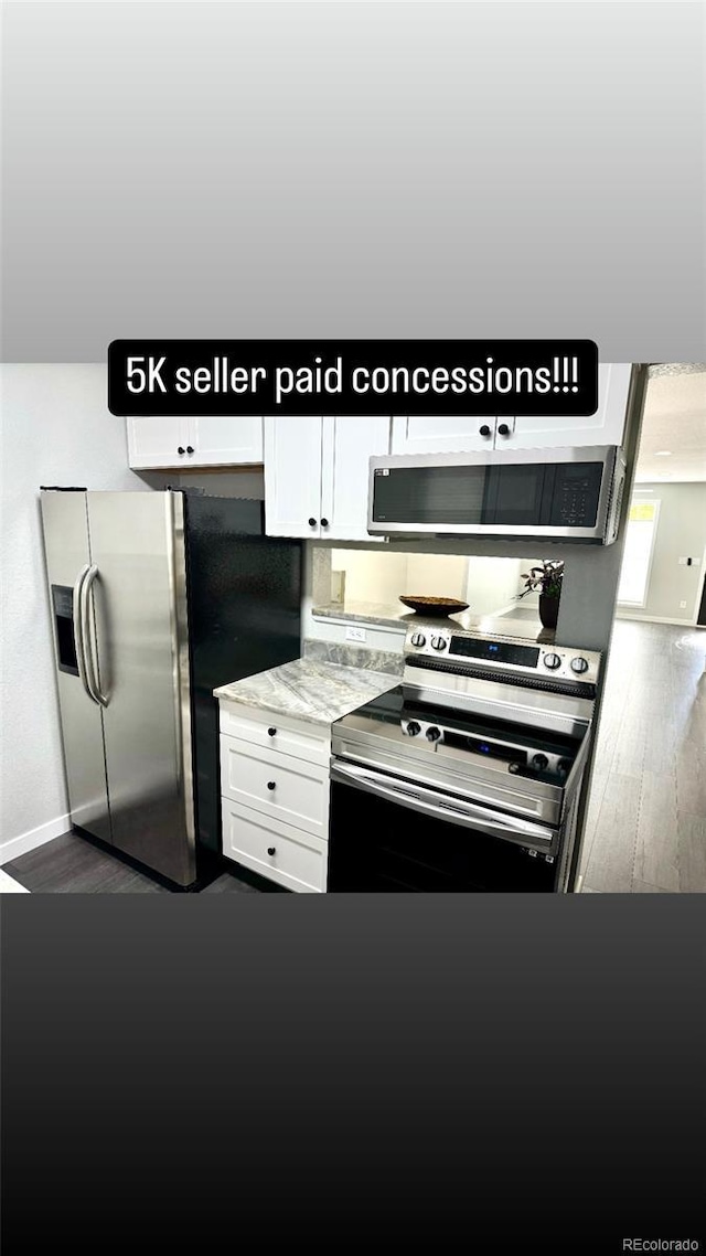 kitchen with light stone countertops, white cabinets, dark hardwood / wood-style floors, and appliances with stainless steel finishes