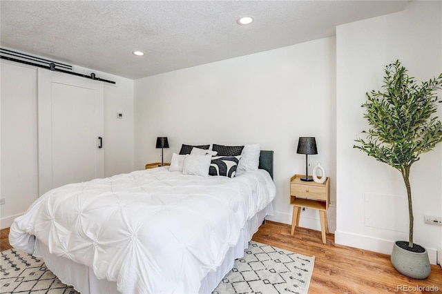 1250 N Humboldt St Unit 202, Denver, CO 80218 - bedroom with a barn door, light wood finished floors, recessed lighting, and a textured ceiling