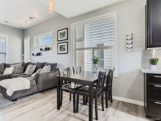 dining space featuring plenty of natural light, track lighting, and light wood-type flooring