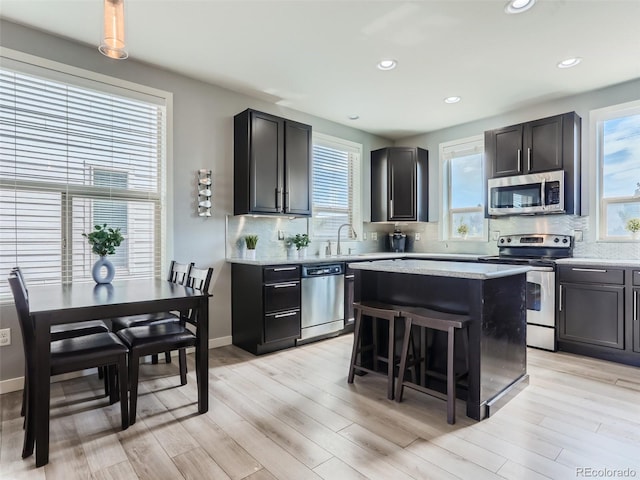 kitchen featuring appliances with stainless steel finishes, a center island, light hardwood / wood-style flooring, and a kitchen breakfast bar