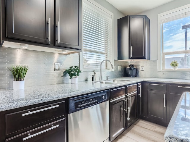 kitchen featuring stainless steel dishwasher, light wood-type flooring, sink, and tasteful backsplash