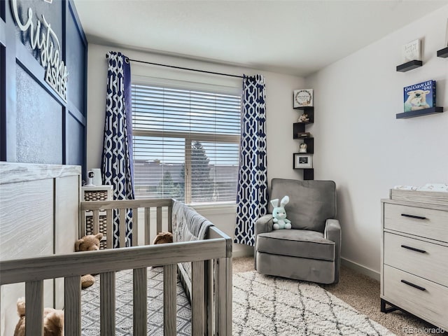 carpeted bedroom featuring a nursery area