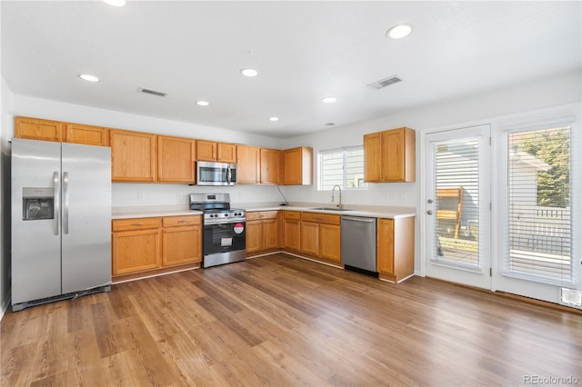 kitchen with appliances with stainless steel finishes, light hardwood / wood-style floors, and sink