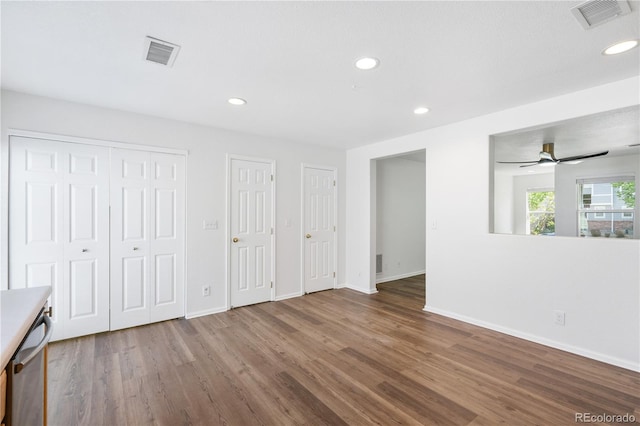 interior space with ceiling fan, multiple closets, and hardwood / wood-style flooring