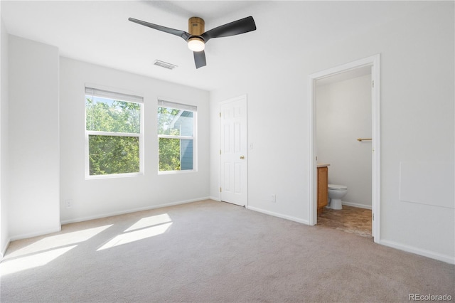 unfurnished bedroom with ceiling fan, a closet, light carpet, and ensuite bathroom