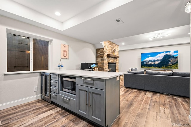 kitchen featuring wine cooler, dark hardwood / wood-style flooring, kitchen peninsula, and gray cabinetry