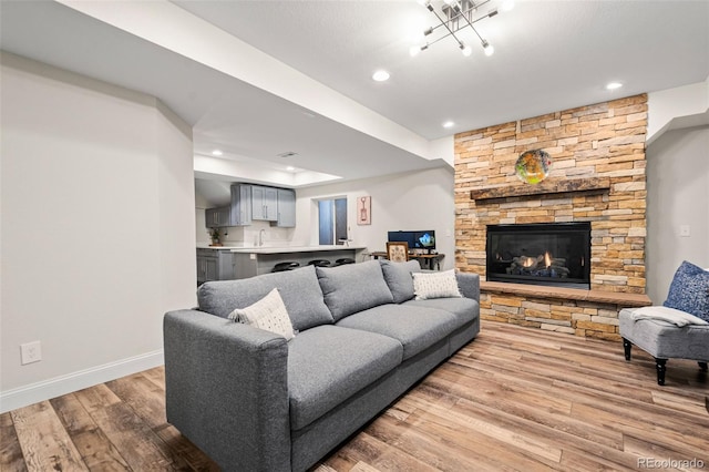 living room with a tray ceiling, a fireplace, and light hardwood / wood-style flooring