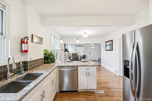 2800 N Fillmore St, Denver, CO 80205 - kitchen featuring stainless steel appliances, wood finished floors, a peninsula, white cabinetry, and decorative light fixtures