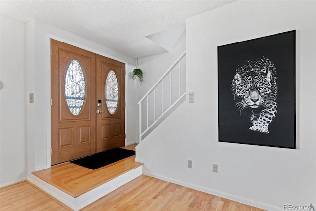 entrance foyer featuring stairway, baseboards, and wood finished floors