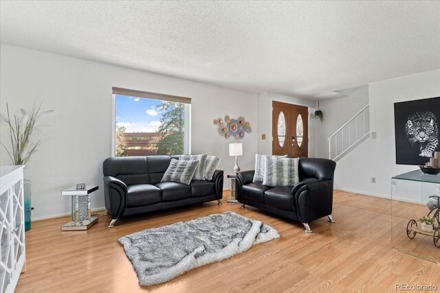 living room with a textured ceiling, wood finished floors, and stairs