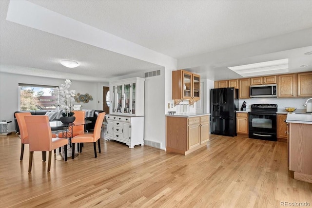 kitchen featuring visible vents, light countertops, black appliances, and light wood-style floors