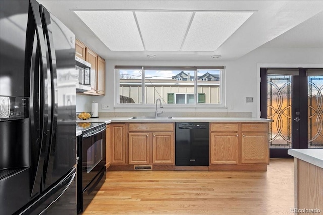 kitchen featuring a sink, visible vents, light wood-type flooring, and black appliances