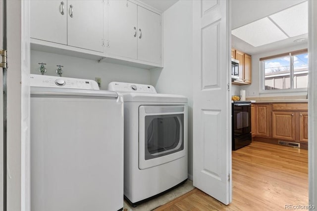 washroom with cabinet space, visible vents, light wood finished floors, and washing machine and dryer