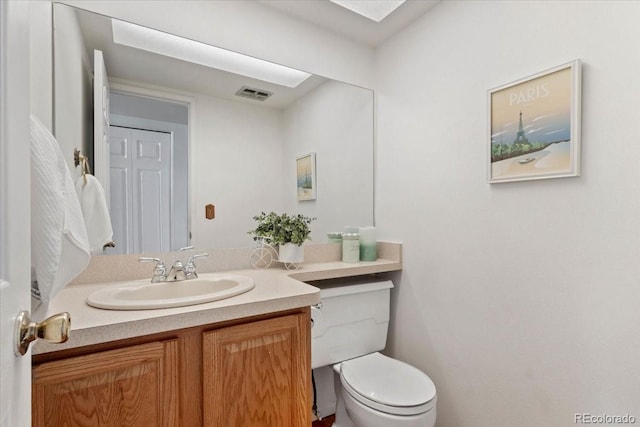 half bathroom featuring visible vents, toilet, and vanity