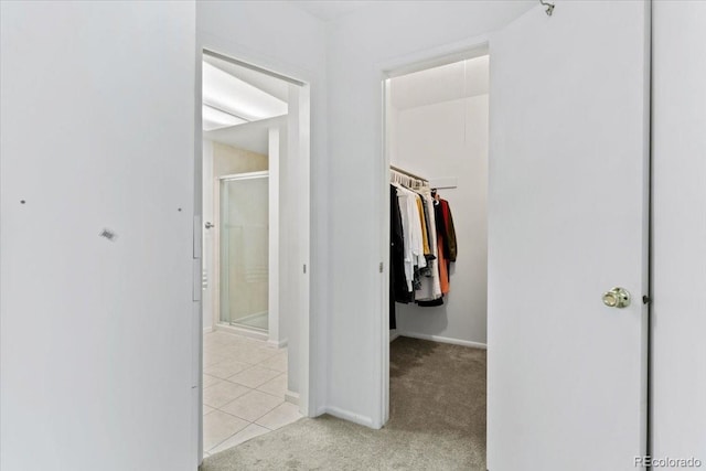 hall featuring light carpet, light tile patterned flooring, and baseboards