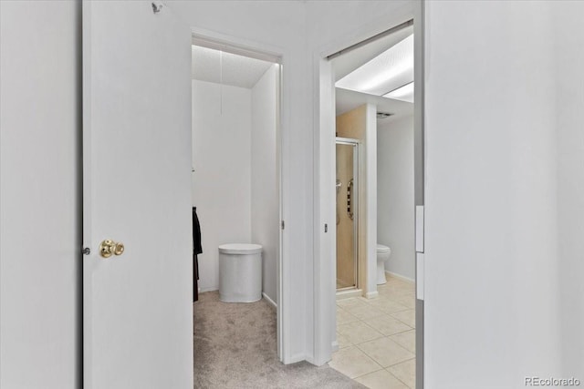 bathroom with a shower stall, tile patterned flooring, baseboards, and toilet