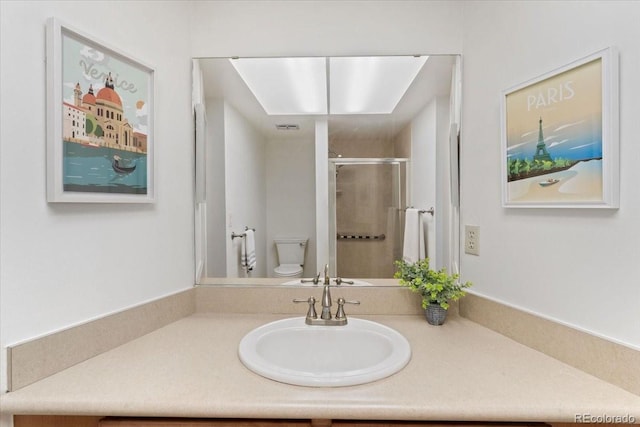 bathroom featuring toilet, a stall shower, and vanity