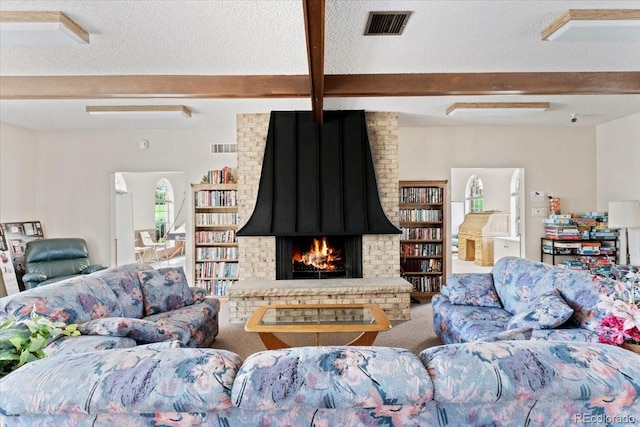 carpeted living room with a fireplace, visible vents, and beamed ceiling
