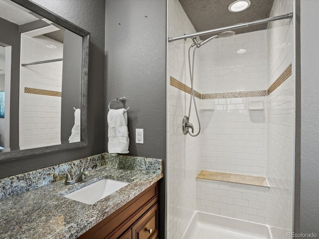 6943 Oak Way, Arvada, CO 80004 - full bath featuring a textured wall, vanity, and tiled shower