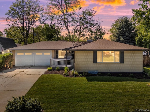 6943 Oak Way, Arvada, CO 80004 - view of front of property featuring driveway, brick siding, a lawn, and a garage