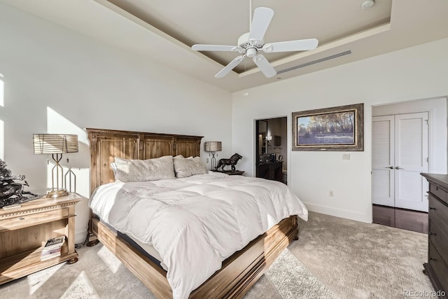 carpeted bedroom with a raised ceiling and ceiling fan