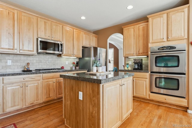 1022 Orion Way, Castle Rock, CO 80108 - kitchen with appliances with stainless steel finishes, light brown cabinetry, arched walkways, light wood-style flooring, and recessed lighting