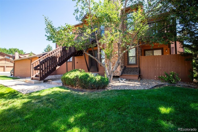 rear view of property featuring stairs, fence, and a yard